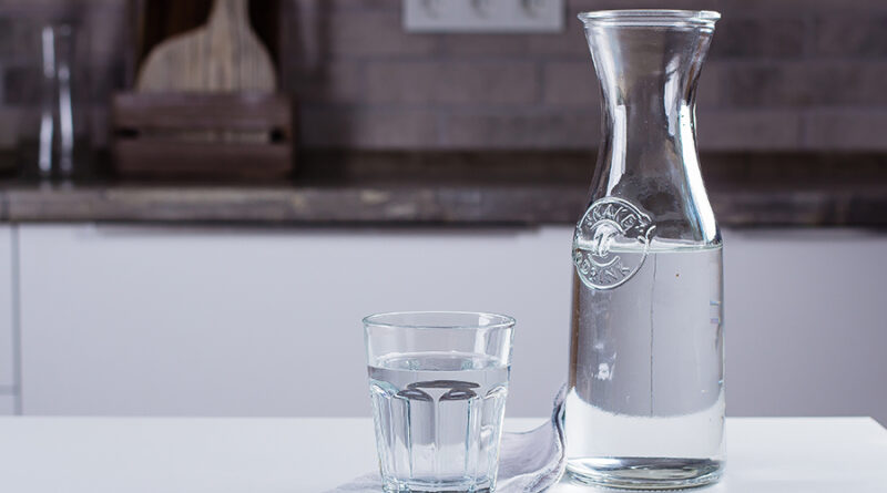 Glass of pure water and bottle on kitchen table.